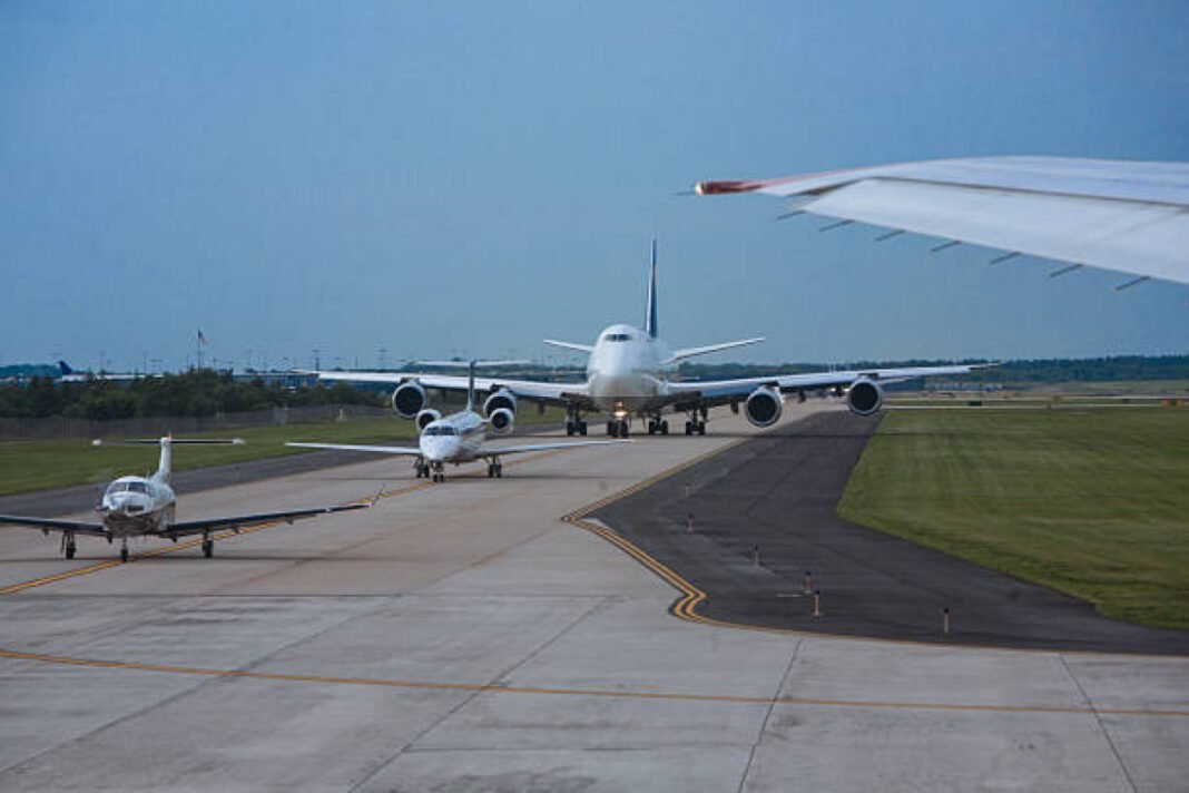 Airplanes big and small lining up on runway for taking off at a busy airport Kota, new airport, tourism, regional connectivity, Airports Authority of India (AAI), Civil Aviation Authority, Urban Development Department, Rajasthan Chief Minister Bhajanlal Sharma, infrastructure, Hadoti region, Kota Development Authority, Jaipur Airport, Udaipur Airport, Uttarlai (Barmer) Airport, civil enclave, air travel, economic development.