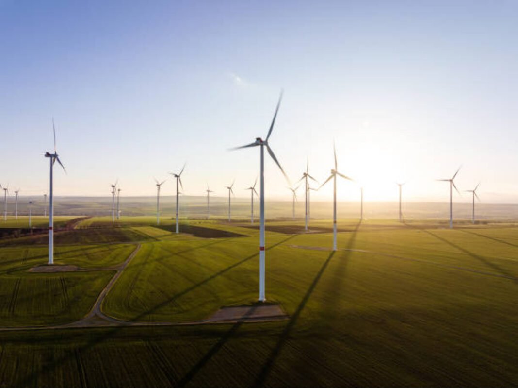 Aerial view of wind turbines with fields in evening light Gujarat, wind power generation, renewable energy, wind energy capacity, offshore wind projects, clean energy, energy transition, India’s renewable targets, sustainable energy.